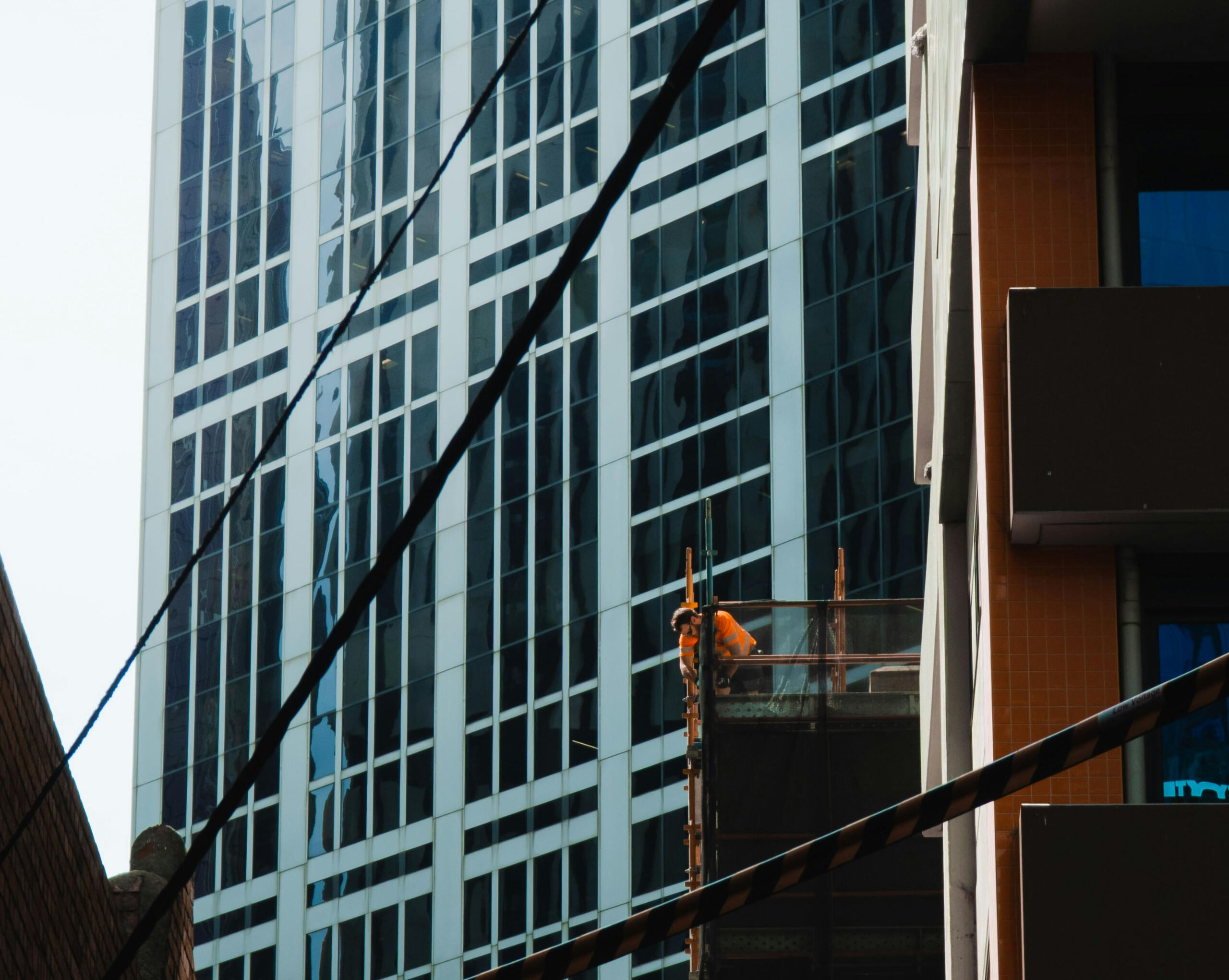 Outside of a building with a man in a high-vis vest working with tools.